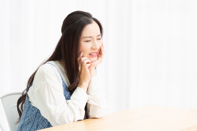 歯が痛くて頬を抑える女性